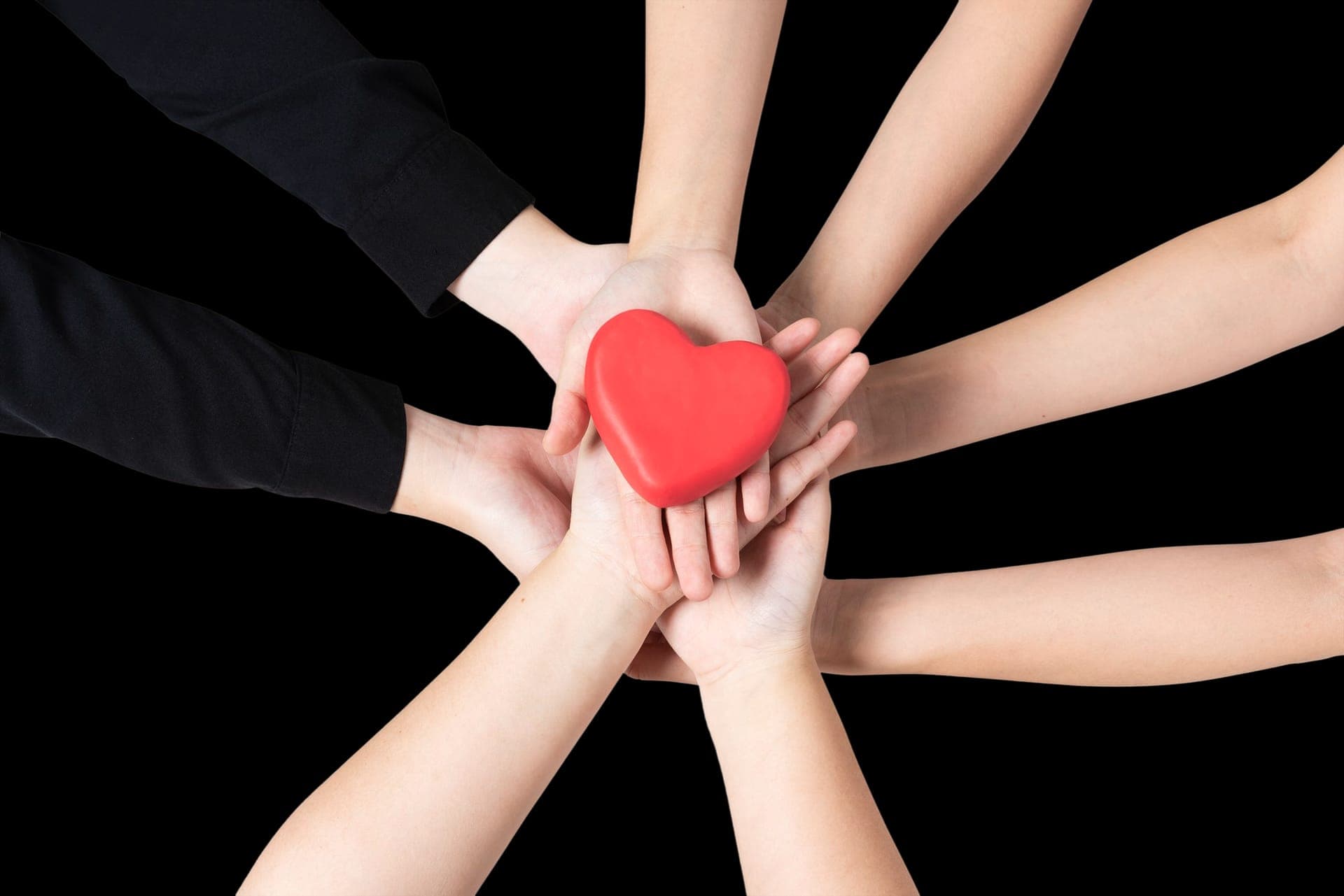 Hands cupped together holding a small red heart.